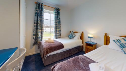 丁格尔Dingle Holiday Homes的一间卧室设有两张床和窗户。