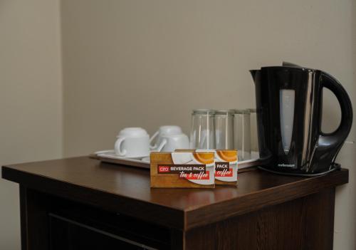 彼得马里茨堡Bayside Hotel Pietermaritzburg的一张桌子,上面放着两罐蜂蜜和一个咖啡壶