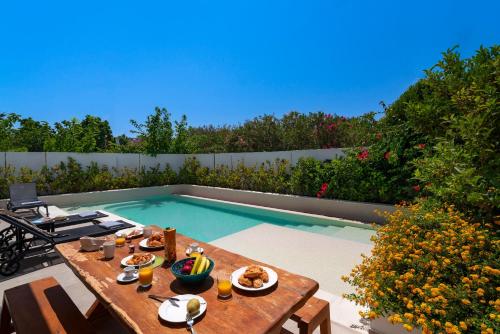 伊利索斯Thalassa Luxury Villa的游泳池旁的餐桌上放着食物