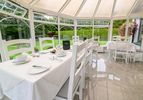 特拉利Ashville House B&B Tralee的白色的用餐室配有白色的桌椅