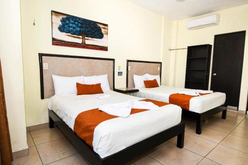 OcozocuautlaHotel los faroles的酒店客房带两张床,带橙色和白色的床单。