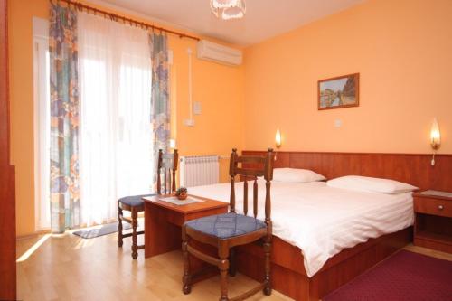 洛夫兰Apartments and rooms with parking space Lovran, Opatija - 2321的一间卧室配有一张床、一把椅子和一张桌子