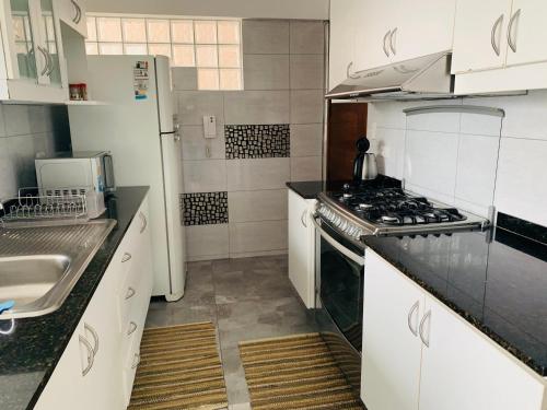 利马Spacious apartment in Miraflores的厨房配有白色橱柜和炉灶烤箱。