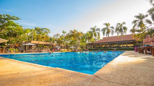 伊瓜苏港堪普勒约美洲酒店的度假村的游泳池,人们在里面游泳
