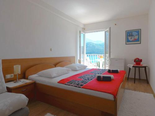 斯拉诺Apartments and rooms by the sea Slano, Dubrovnik - 2682的一间卧室配有一张带红色毯子的床和窗户。