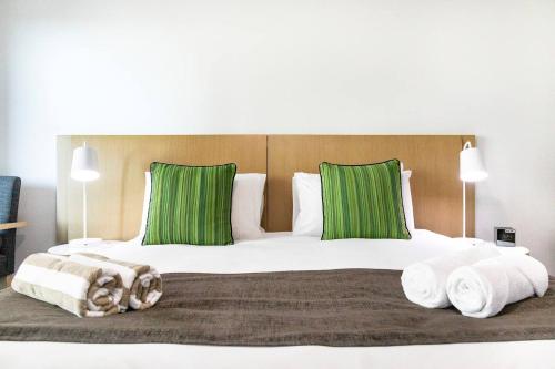 达尔文King Balcony Suite at Resort Style Darwin Stay的一间卧室配有一张带绿色枕头的大床