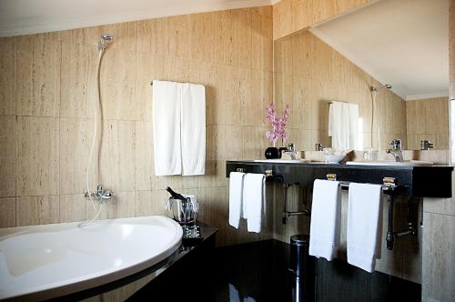 Santa Eugenia de Berga阿鲁米酒店的浴室配有大型白色浴缸和2个盥洗池