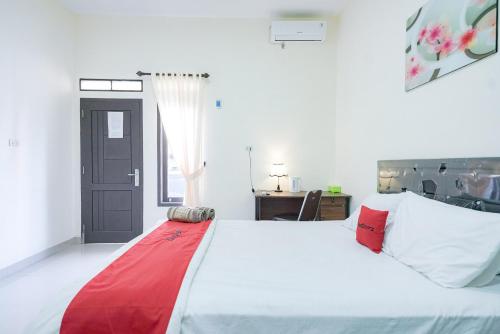 KedatonRedDoorz @ Jalan Urip Sumoharjo Lampung的卧室配有一张大白色床和红色毯子