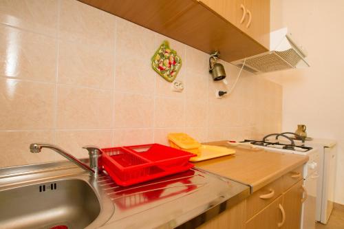 卢卡瓦克Apartment Milna 2461c的厨房柜台在水槽上设有红色托盘