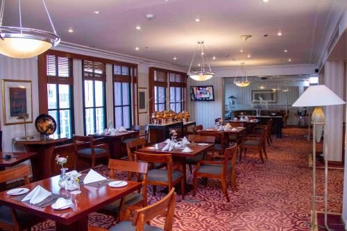 雅加达红顶会议中心酒店 的餐厅设有木桌、椅子和窗户。