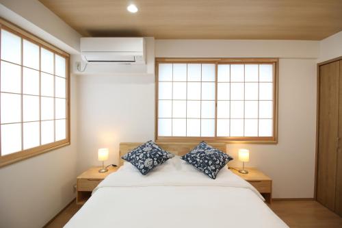 东京Uhome Suido Apartment SD的卧室配有白色的床和2扇窗户。