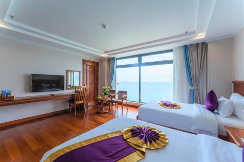 归仁Vietnam Taste Hotel Quy Nhon - Beachfront的酒店客房设有两张床和电视。
