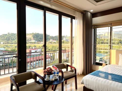 老街市Khách sạn Ngọc Hà的一间卧室配有一张床、一张桌子、椅子和窗户。