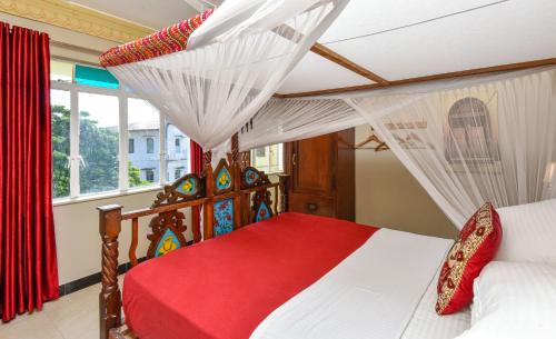 桑给巴尔Freddie Mercury Apartments的一间卧室配有一张带红色毯子的天蓬床
