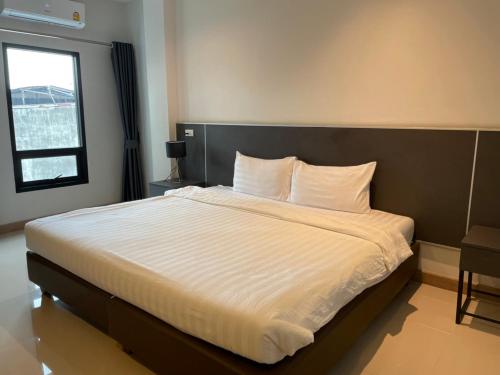 Sinsiri hostel的卧室配有一张带白色床单的大床和窗户。