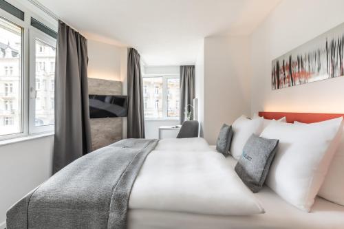 威斯巴登Select Hotel Wiesbaden City的酒店客房配有一张带白色枕头的大床