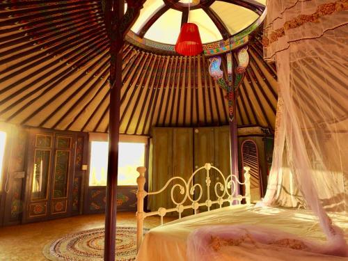 加藤德雷Exclusive Nirvana yurts Glamping的蒙古包内一间卧室,配有一张天蓬床