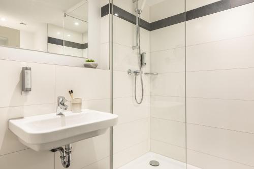 美因茨美因茨精选酒店的白色的浴室设有水槽和淋浴。
