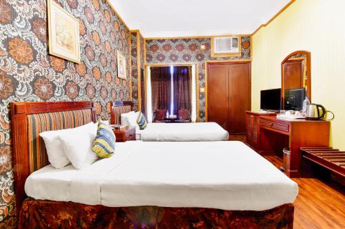 麦纳麦Capital O 125 Moon Plaza Hotel的酒店客房设有两张床和电视。