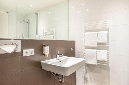 杜塞尔多夫麦迪逊杜塞尔多夫火车总站诺富姆酒店的白色的浴室设有水槽和镜子