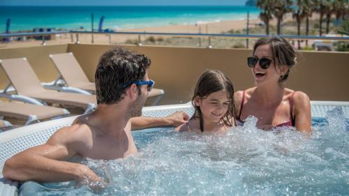 佩尼斯科拉RH卡萨布兰卡套房酒店的热水浴池里的男女和小女孩