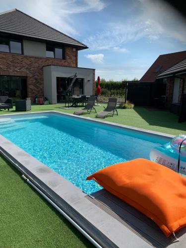 LorgiesLes Chambres de Lily 2的一座游泳池,旁边是一座房子,上面有橙色枕头