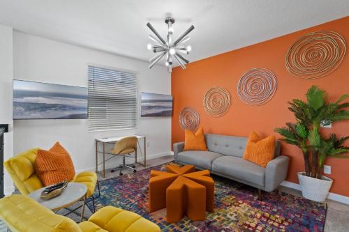 基西米Beautiful Family Villa - Pool and Hot Tub - Near Disney World的客厅拥有橙色的墙壁,配有沙发和椅子