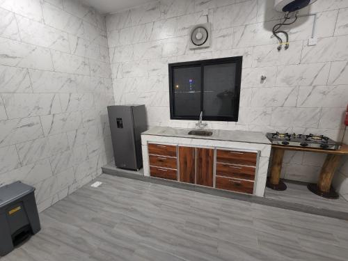 Al ‘AqarAlshafaq chalet的配有电视和带水槽的台面的房间