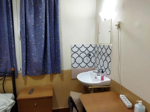 雅典SAN REMO HOSTEL的一间带水槽的小浴室和一张桌子及一张桌子