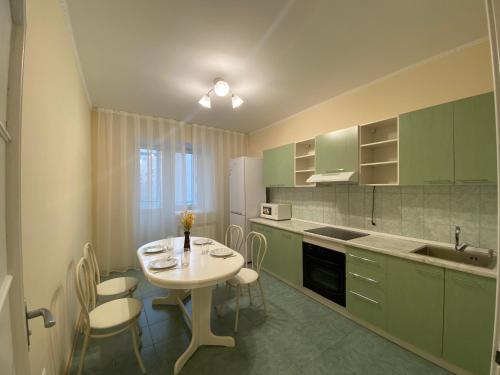 阿斯塔纳Апартаменты в центре города的厨房配有绿色橱柜和桌椅