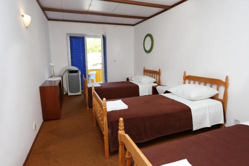 拉茨斯切Rooms by the sea Racisce, Korcula - 3095的客房设有两张床、一张桌子和一台电视机。
