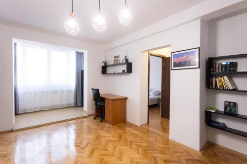 特尔古穆列什Central Apartment Targu Mures的一间带书桌的客厅和一间卧室
