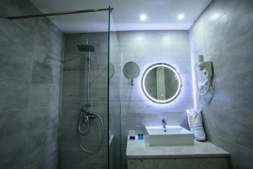 拉马萨Suites Hôtel Les Charmilles & Spa的带淋浴、盥洗盆和镜子的浴室