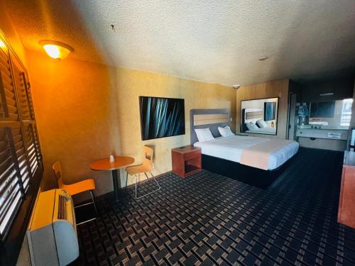 斯坦顿Casa Playa Inn & Suites Stanton Anaheim Area的酒店客房设有一张床和一张小桌子。