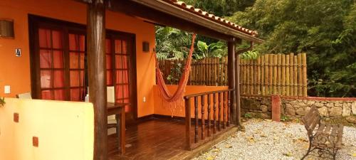 阿布拉奥Casa da Ilha Inn, Ilha Grande的橙色的房子,设有门廊和围栏