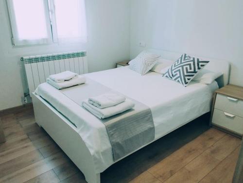 潘普洛纳Precioso apartamento en Pamplona junto al centro的一张白色的大床,带两条毛巾