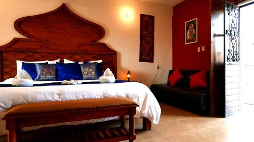 圣克里斯托瓦尔-德拉斯卡萨斯Ganesha Hotel的一间卧室设有一张大床,拥有蓝色和红色的墙壁