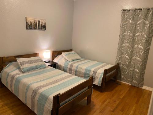 斯普林菲尔德Cozy house with large free parking on premises的一间卧室设有两张床,在木地板上配有一盏灯。