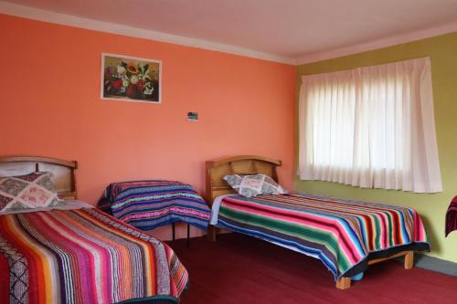 奥科苏尤LOVELAND AMANTANI LODGE - Un lugar encantado的橙色墙壁客房的两张床