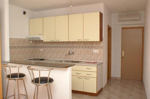 赫瓦尔Apartments and rooms by the sea Milna, Hvar - 3074的厨房配有白色橱柜和2个酒吧凳