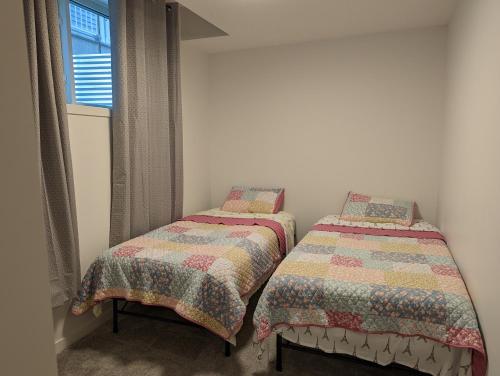 卡尔加里Livingston Howse Haven - A simple & cozy private two-bedroom basement suite with free parking的带窗户的客房内设有两张单人床。