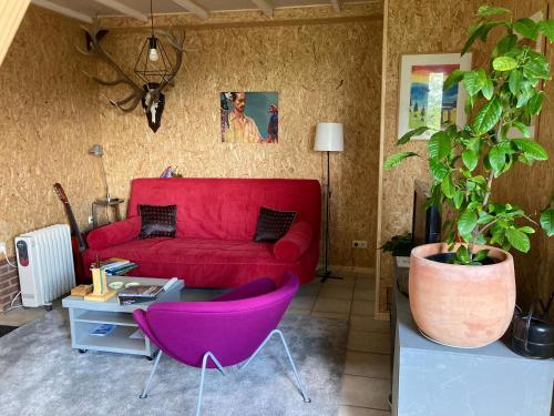 Vakantiehuisje De Waddenuil的客厅配有红色沙发和紫色椅子