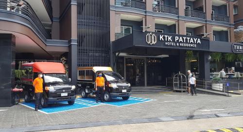 芭堤雅市中心KTK Pattaya Hotel & Residence的两辆汽车停在大楼前的停车场