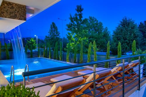 约阿尼纳Selin Luxury Residences的一个带椅子的甲板和晚上的游泳池