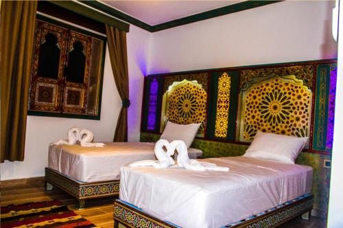 舍夫沙万Riad Azemmat的一间卧室配有两张带白色床单的床