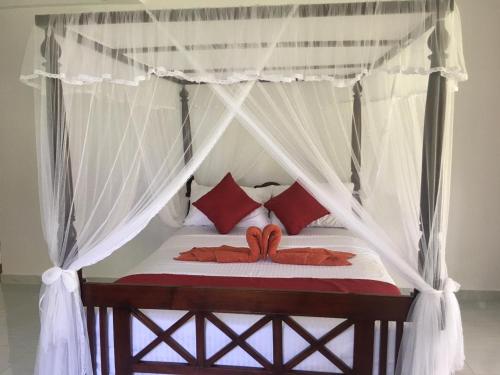 陶尔佩Lush Green Villa的一间卧室配有一张带红色枕头的天蓬床