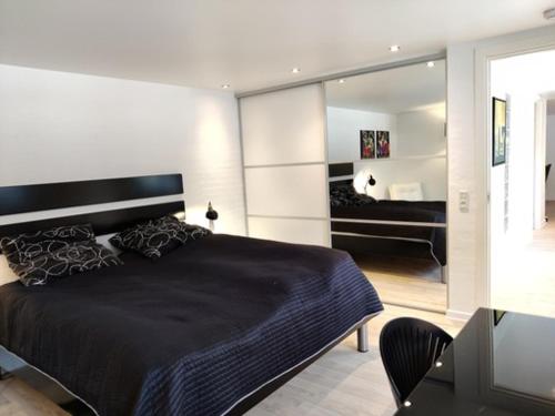 海宁Værelser i midtbyen的一间卧室配有一张大型黑色床和镜子