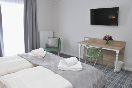 BasthorstLandhaus Hamester - Hotel & Restaurant - neu eröffnet September 2022的酒店客房设有两张床、一张桌子和一台电视。