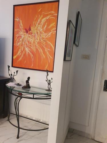 内坦亚CHAMBRE BLEUE 2 PERSONNES的走廊上的玻璃桌,墙上挂着一幅画