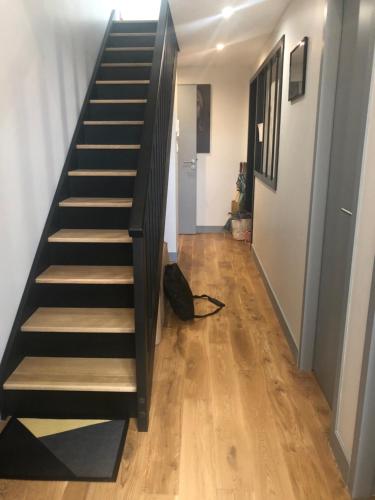 拉罗谢尔Appart Christelle的楼梯通往铺有木地板的走廊